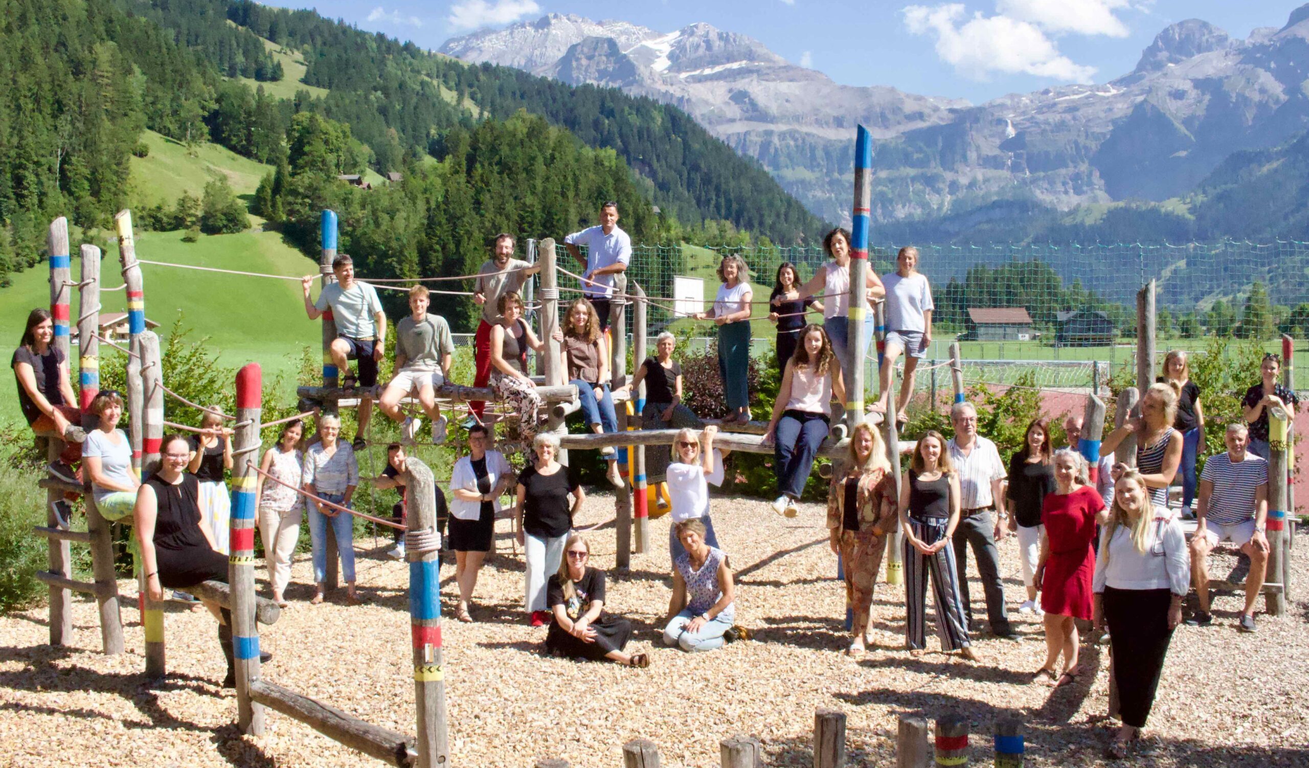 Alle Lehrpersonen der Schule Lenk verteilt auf dem Spielplatz des Schulhausplatzes an der Lenk vor toller Kulisse aus Bergen.