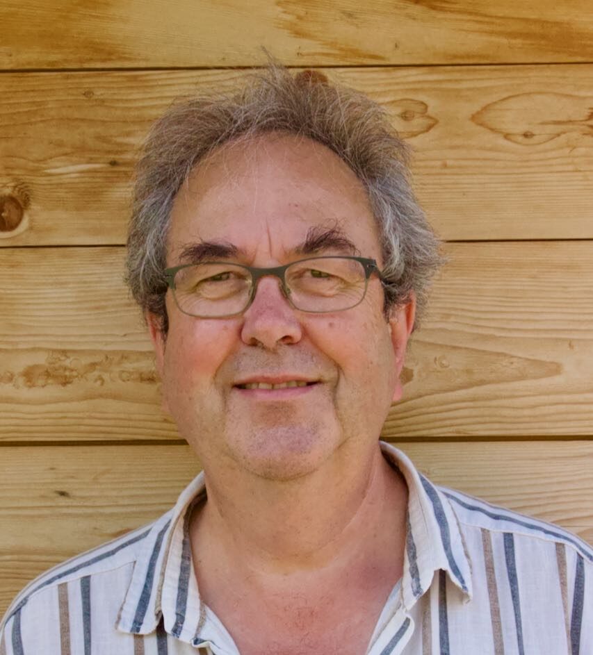 Lehrer und Schulleiter Jürg Niederhauser vor hölzerner Wand als Hintergrund.
